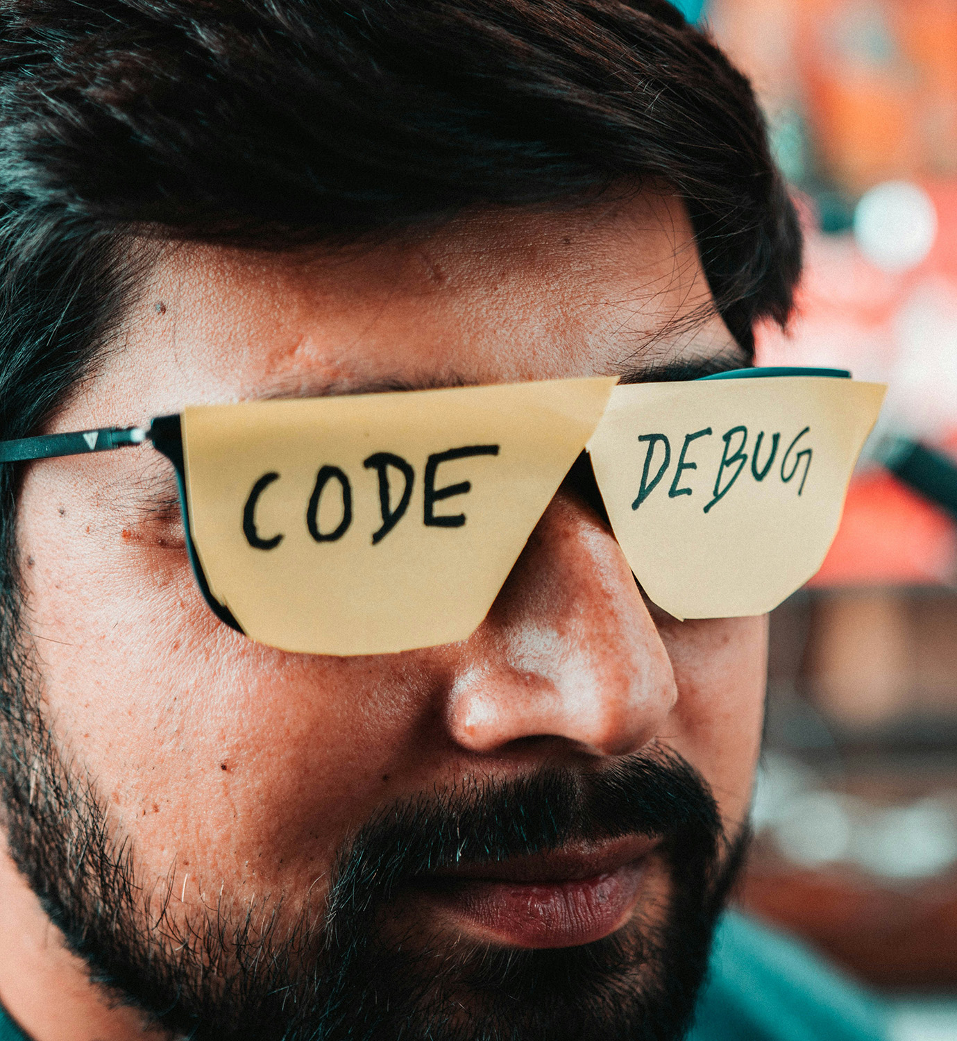 Mann mit Brille, die mit den Wörtern "Code" und "Debug" beklebt ist.